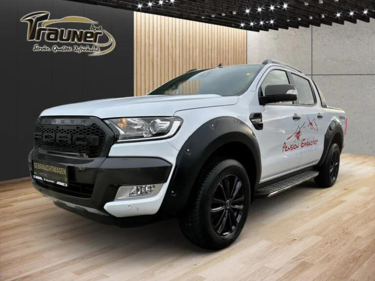 Ford Ranger Wildtrak Doppelkabine in weiß, ausgestattet mit Offroad-Reifen, vor modernem Hintergrund.